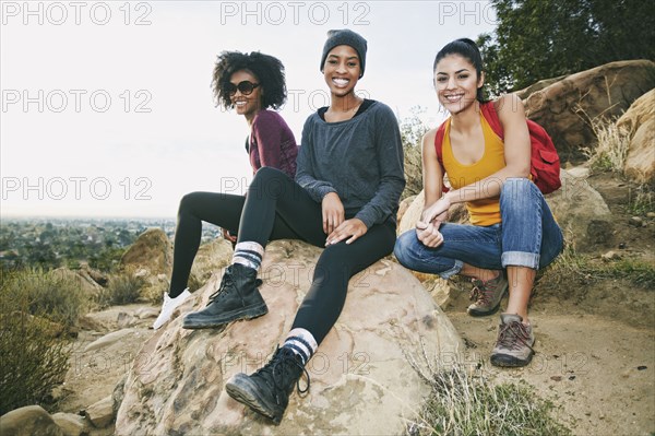 Portrait of smiling women sitting on rock