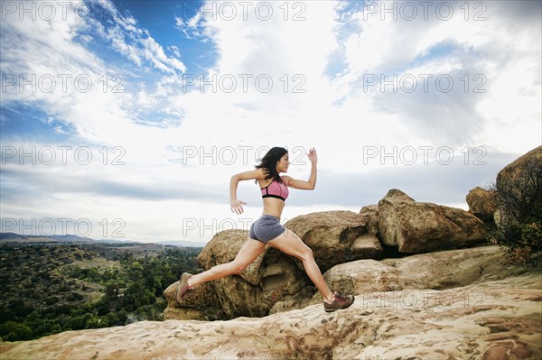 Hispanic woman running on rock formation