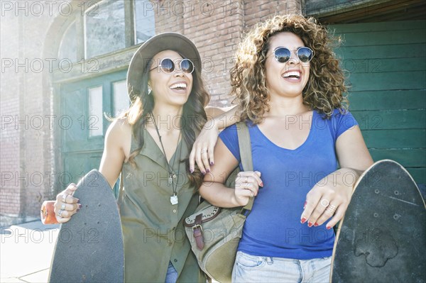 Mixed Race women holding skateboards in city