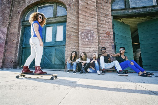 Friends watching woman skateboarding on sidewalk