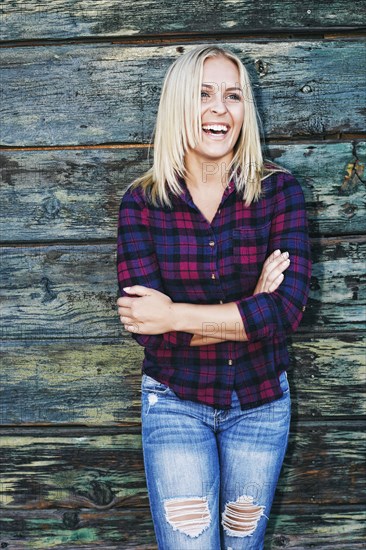 Portrait of smiling Caucasian woman leaning on wooden wall