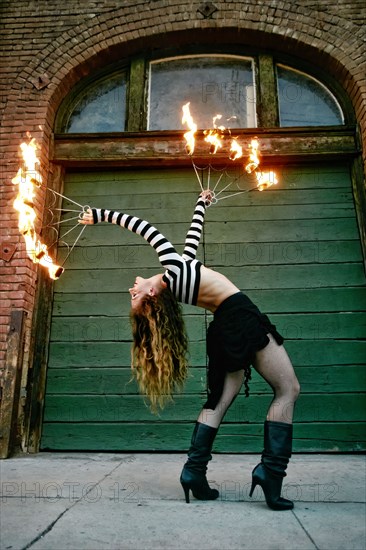 Caucasian woman juggling fire on city sidewalk