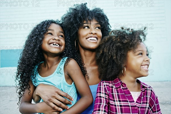 Smiling mother and daughters looking away