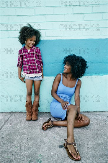 Smiling mother and daughter relaxing on sidewalk