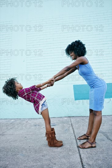 Smiling mother and daughter playing on sidewalk