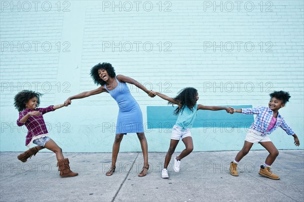 Girls pulling arms of woman in opposite directions