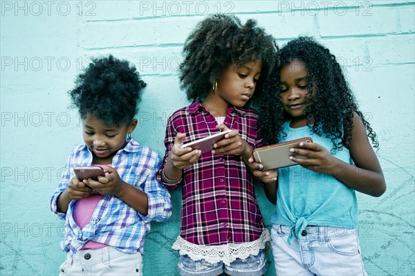 Girls leaning on wall texting on cell phones