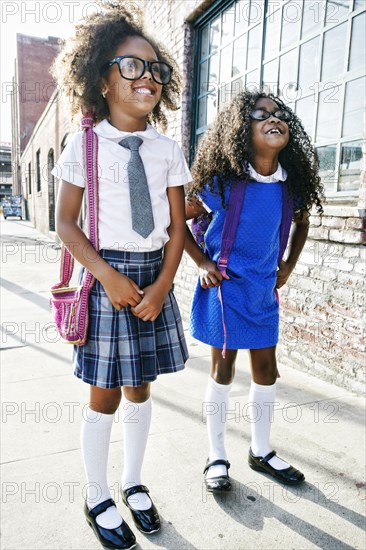 Smiling girls standing on sidewalk ready for school