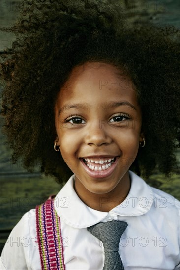 Portrait of smiling Mixed Race girl near wooden wall