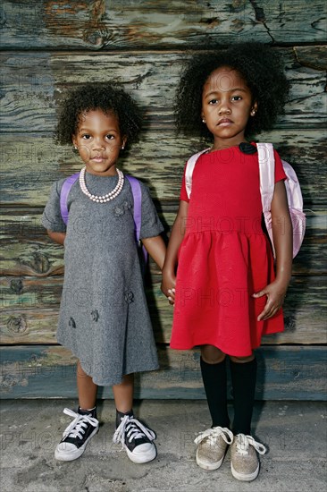 Portrait of serious girls standing near wooden wall