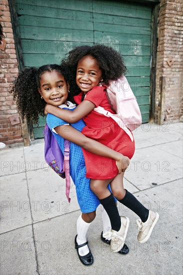 Portrait of smiling girl lifting friend on sidewalk