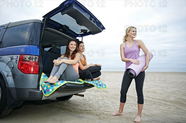Smiling Caucasian women on beach with car
