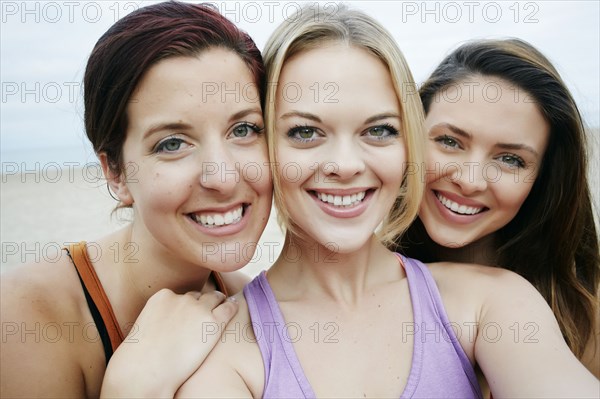 Portrait of smiling Caucasian women cheek to cheek on beach