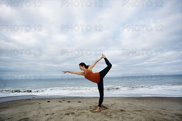 Caucasian woman performing yoga on beach