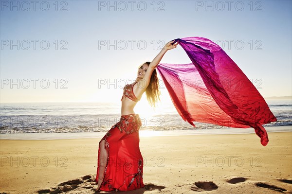 Caucasian belly dancer holding scarf on beach