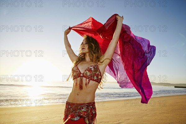 Caucasian belly dancer holding scarf on beach