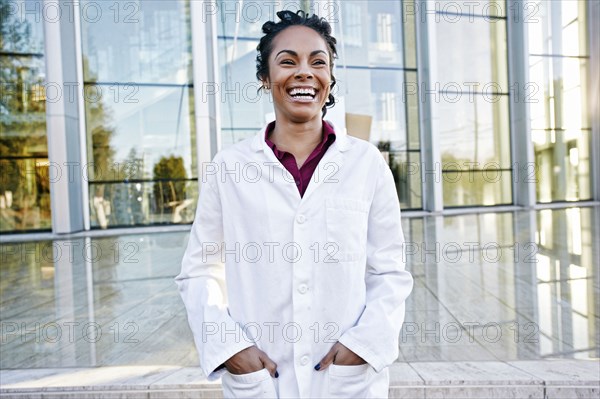 Portrait of laughing Mixed Race doctor outdoors at hospital
