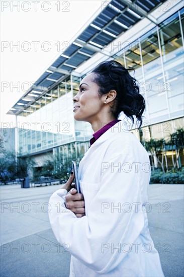 Portrait of smiling Mixed Race doctor holding digital tablet outdoors