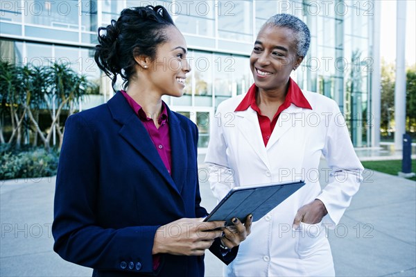 Doctor and administrator outdoors at hospital using digital tablet