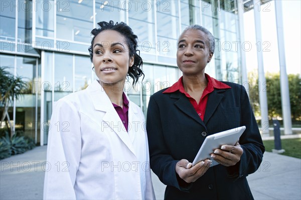 Doctor and administrator outdoors at hospital using digital tablet