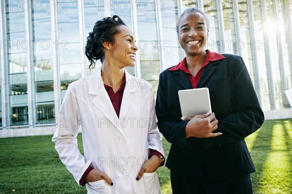 Doctor and administrator laughing outdoors at hospital