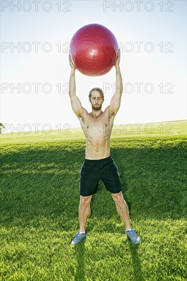 Caucasian man exercising with fitness ball in field
