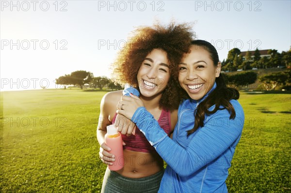 Women hugging and laughing in sunny field