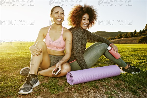 Smiling women sitting in sunny field