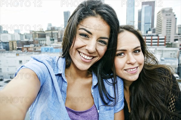 Smiling Hispanic women posing on urban rooftop