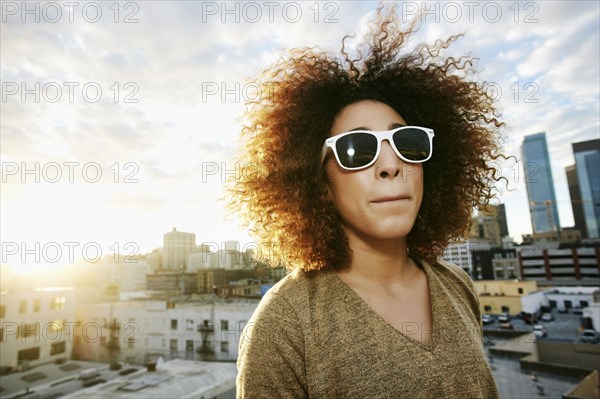 Portrait of serious Hispanic woman on urban rooftop at sunset