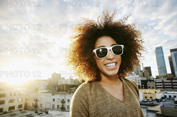 Portrait of smiling Hispanic woman on urban rooftop at sunset