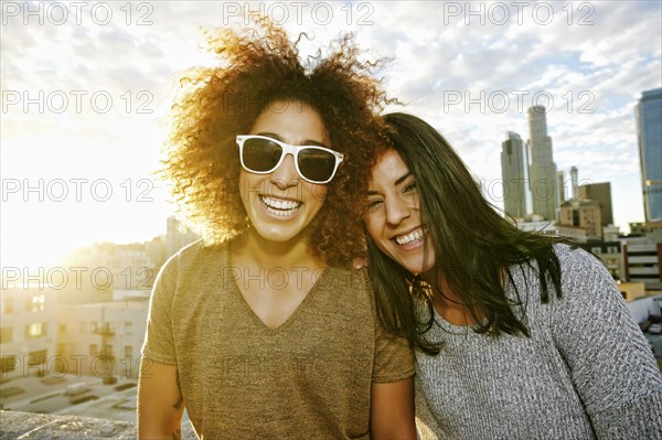 Portrait of smiling Hispanic women on urban rooftop at sunset