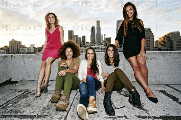 Portrait of smiling women on urban rooftop at sunset