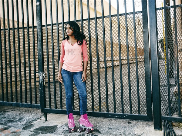 Black woman wearing roller skates near metal gate