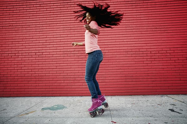 Black woman dancing on roller skates on sidewalk
