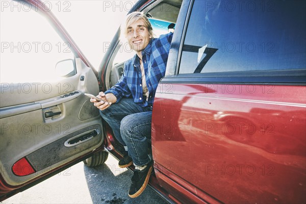 Caucasian man sitting in car texting on cell phone