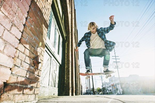 Caucasian man jumping on skateboard on urban sidewalk
