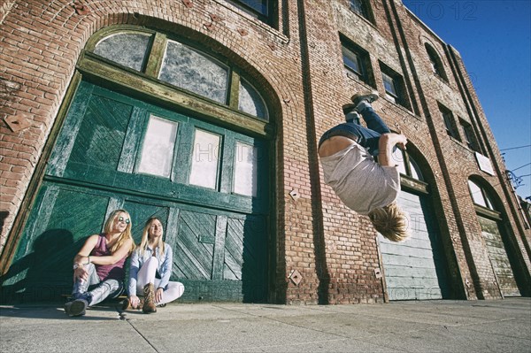 Woman watching man skateboarding on urban sidewalk