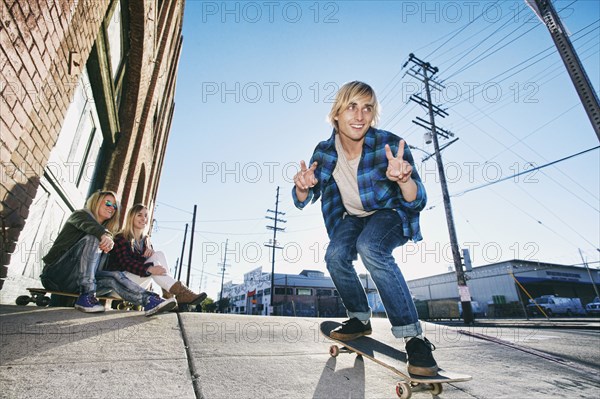Women watching man skateboarding on urban sidewalk