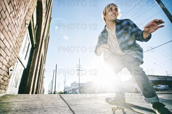 Caucasian man skateboarding on urban sidewalk