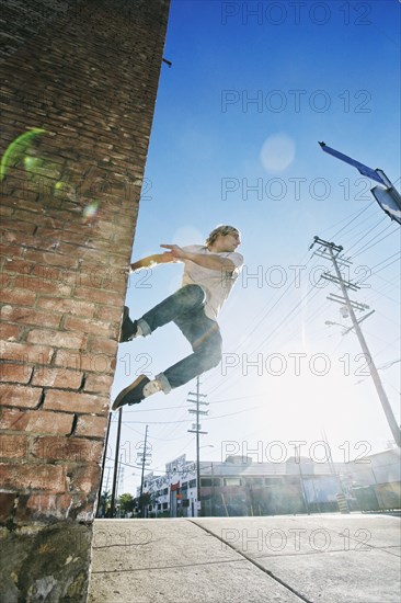 Caucasian man jumping on urban wall