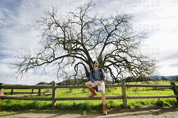 Caucasian man resting on wooden fence