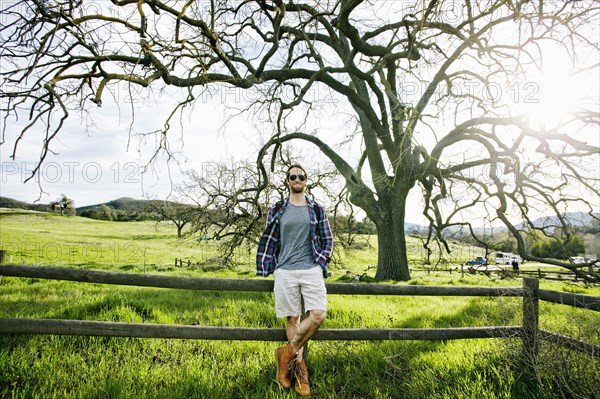 Caucasian man resting on wooden fence