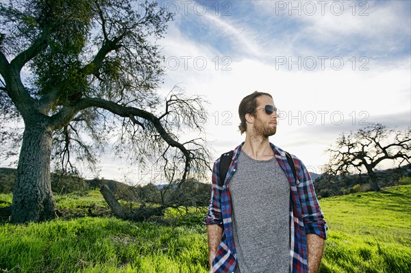 Caucasian man standing in field near tree