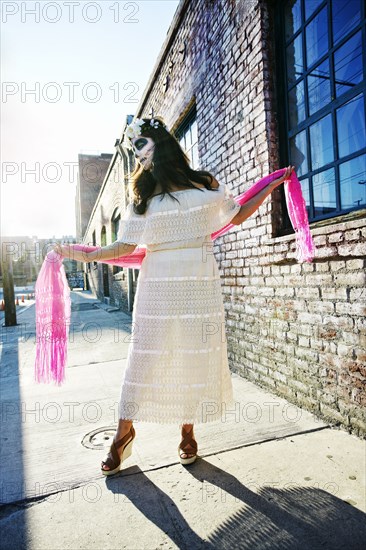 Mixed Race woman dancing on sidewalk wearing skull face paint