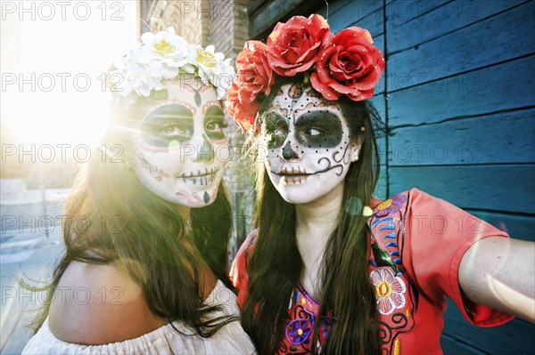 Women on sidewalk wearing skull face paint