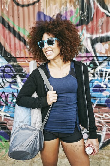 Hispanic woman standing near graffiti wall