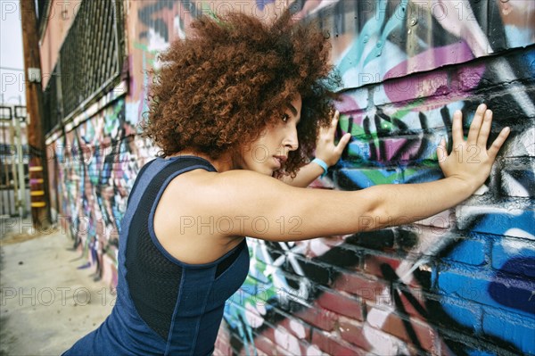 Hispanic woman leaning on graffiti wall