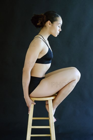 Mixed Race woman wearing underwear sitting on stool