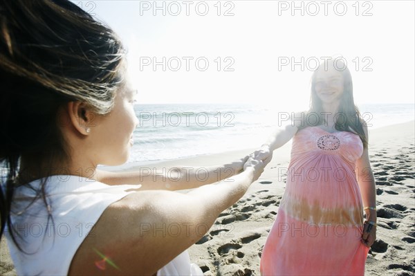 Women holding hands at beach